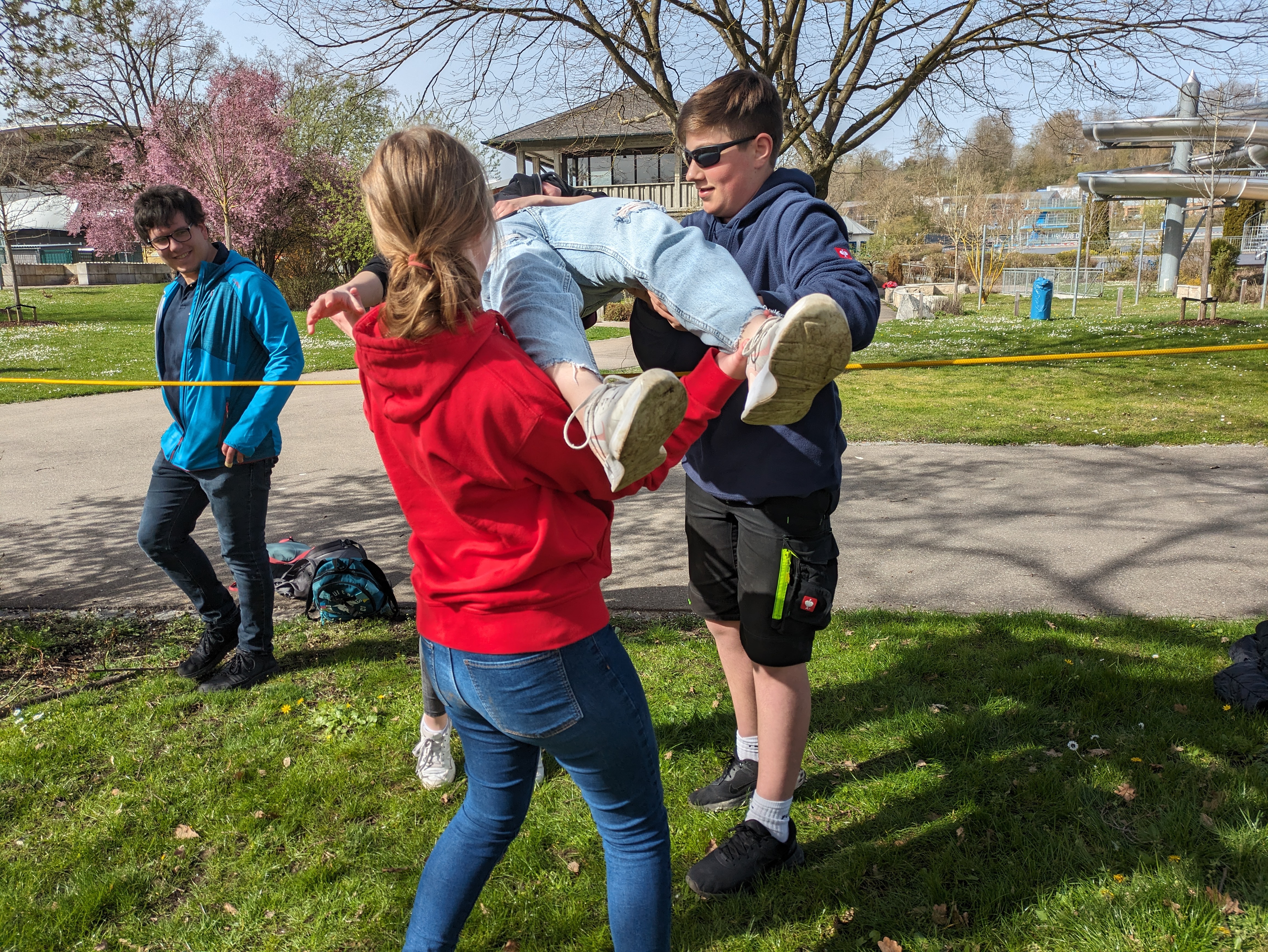 Team-Building: Ein Mitglied der Gruppe wird über die Leine gehoben
