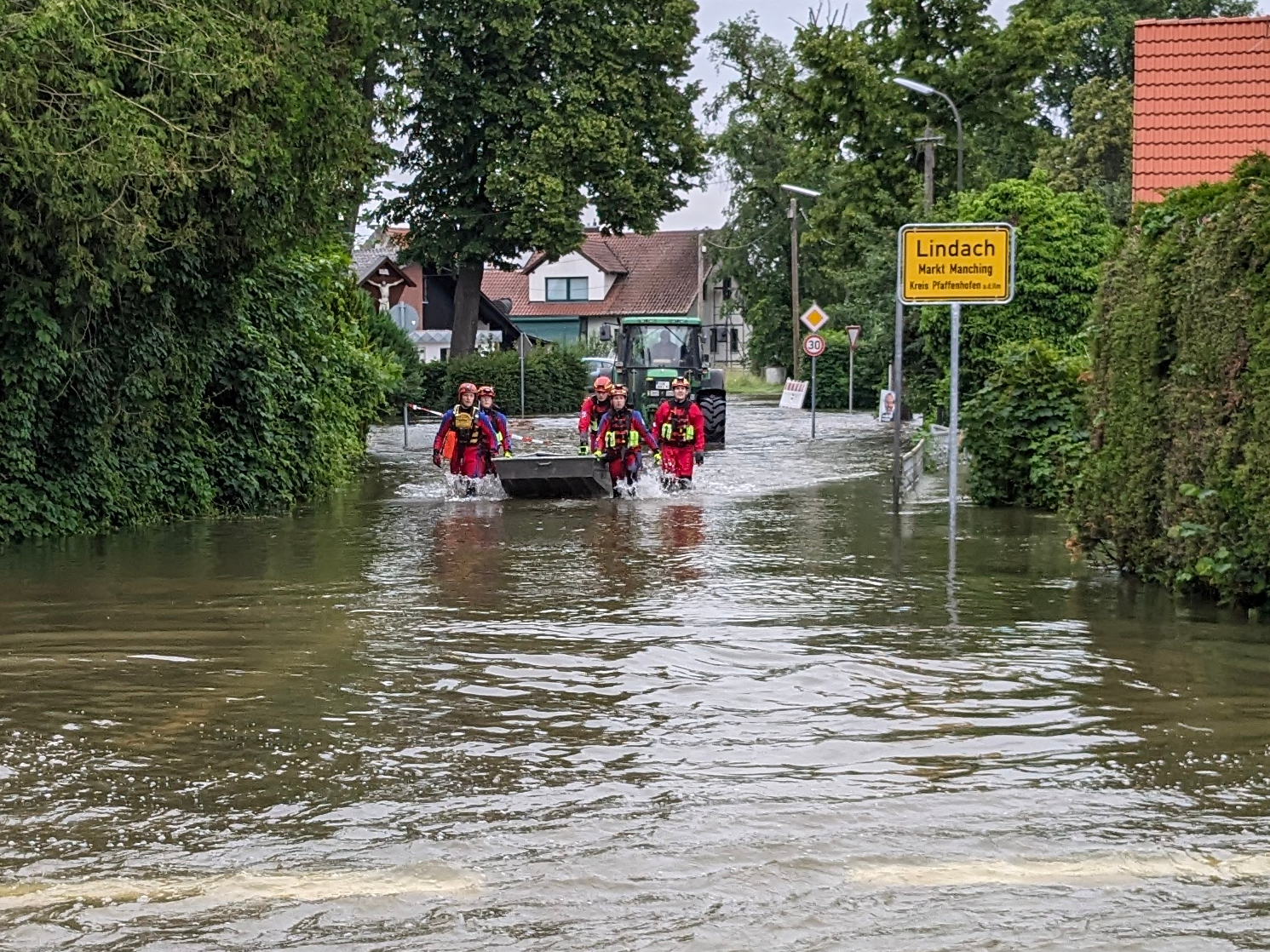 Wasserretter schieben ein Boot auf überschwemmter Zufahrt nach Lindach