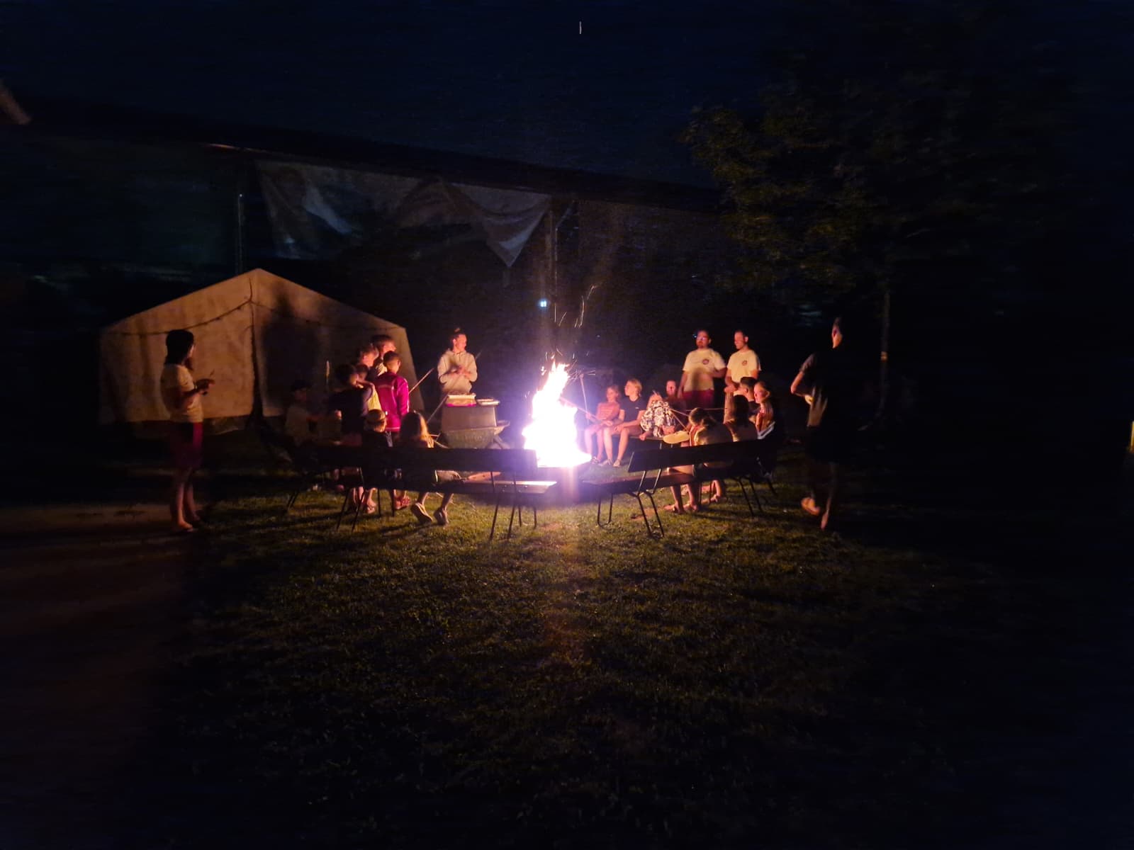 Kinder sitzen um ein Lagerfeuer