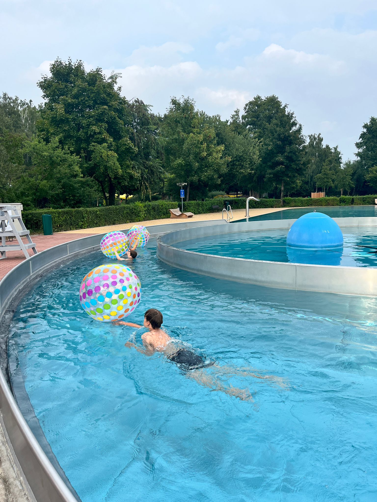 Junge schiebt einen großen Wasserball vor sich her